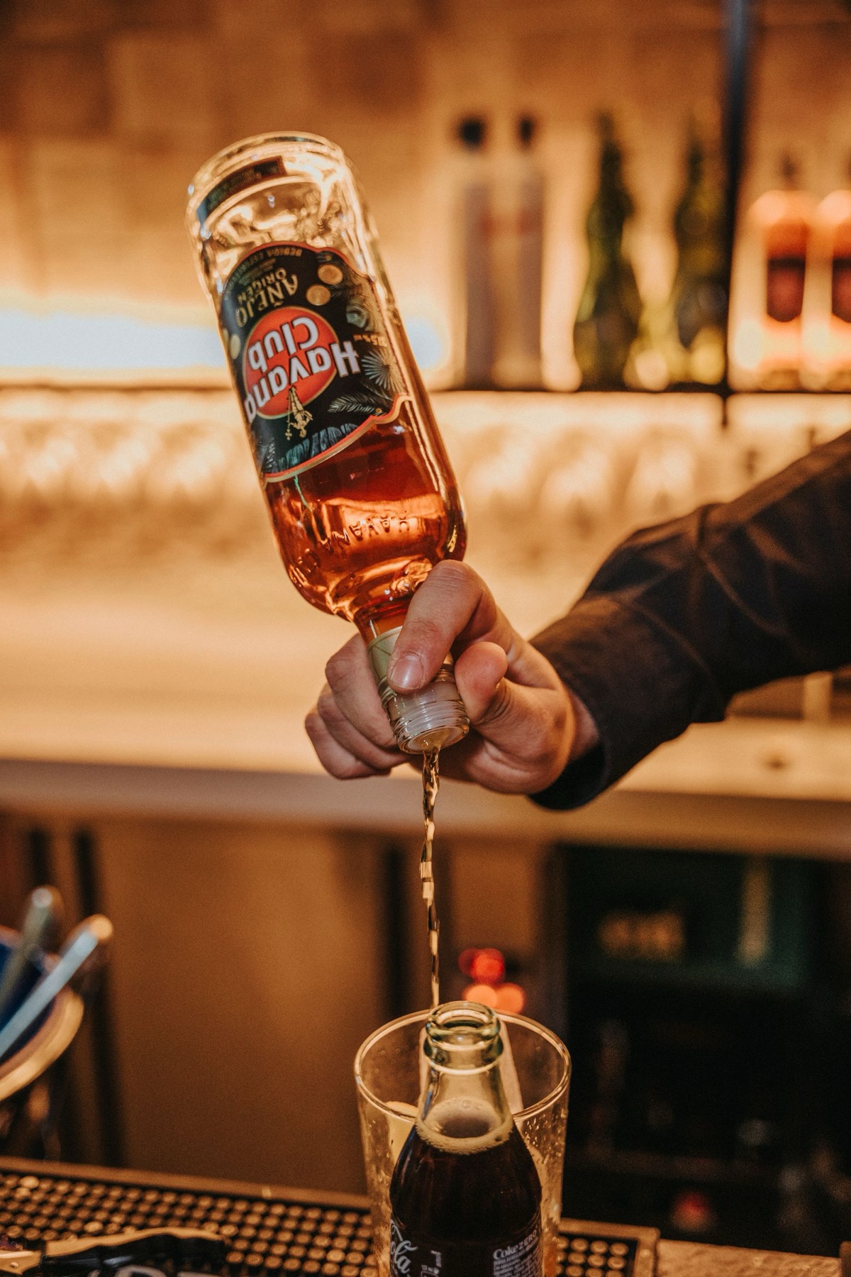 A bartender pouring aged rum behind the bar